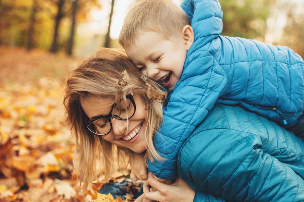 Woman with Glasses and Child Playing in Leaves
